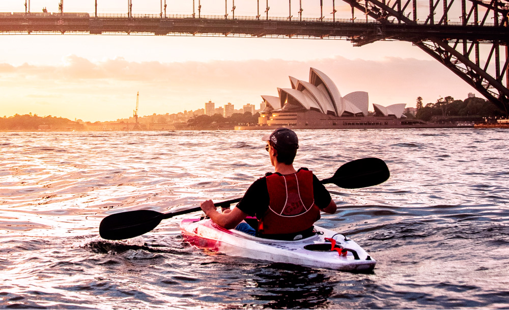 An independent consultant kayaking on Sydney Harbour at sunset